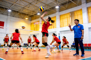 中国女排队员在训练馆进行扣球训练，教练在场边指导